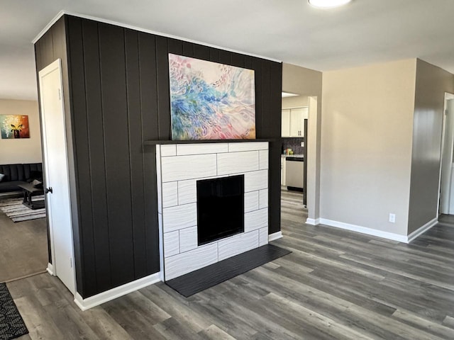 living room featuring a fireplace with flush hearth, wood finished floors, and baseboards