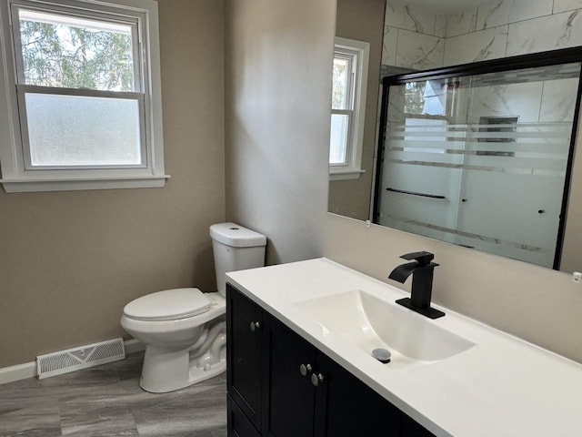 bathroom featuring visible vents, toilet, a shower stall, baseboards, and vanity