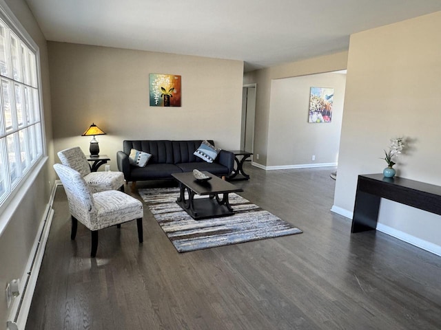 living room with a baseboard heating unit, baseboards, and wood finished floors