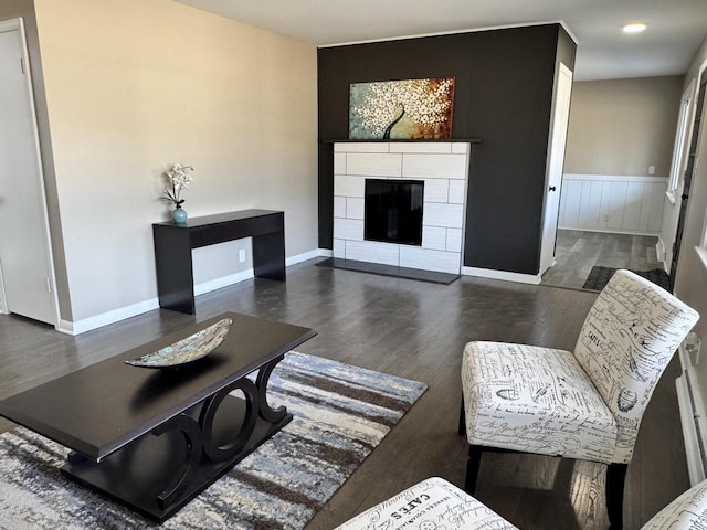 living area featuring wainscoting, baseboards, wood finished floors, and a tiled fireplace