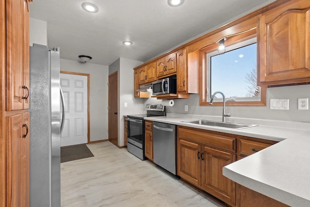 kitchen featuring light countertops, brown cabinetry, marble finish floor, stainless steel appliances, and a sink