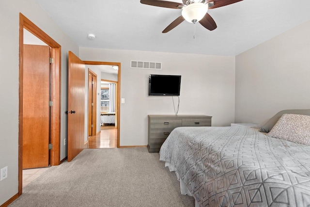 bedroom with visible vents, baseboards, light colored carpet, and a ceiling fan