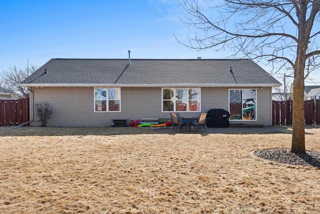 rear view of house with roof with shingles and fence