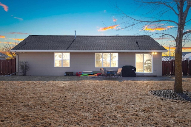 back of property at dusk featuring a patio, fence, and roof with shingles