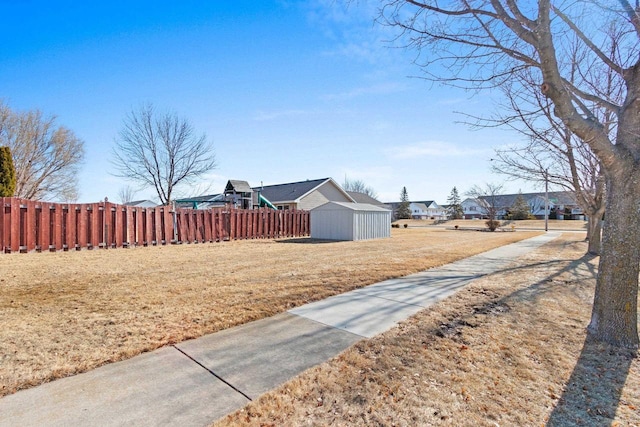 view of yard with a shed, a residential view, an outdoor structure, and fence