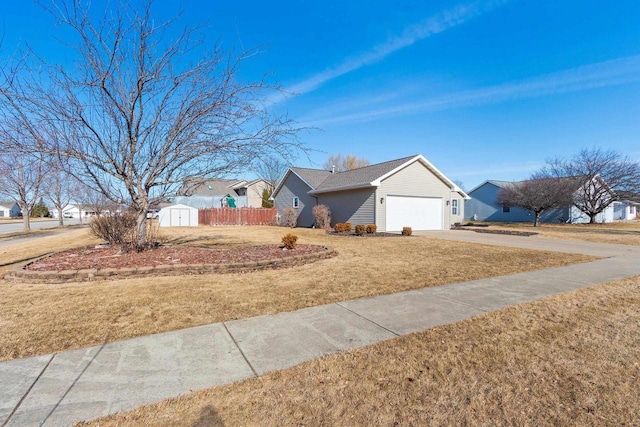 ranch-style home featuring an attached garage, a front lawn, fence, a storage shed, and driveway