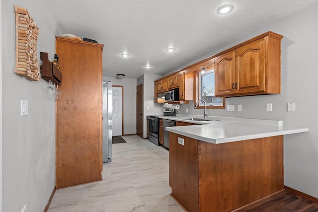 kitchen with light countertops, a peninsula, brown cabinetry, stainless steel appliances, and a sink