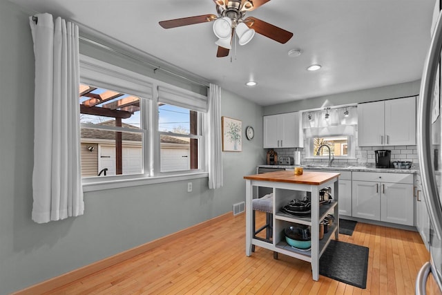 kitchen with visible vents, white cabinets, wood counters, tasteful backsplash, and light wood-type flooring