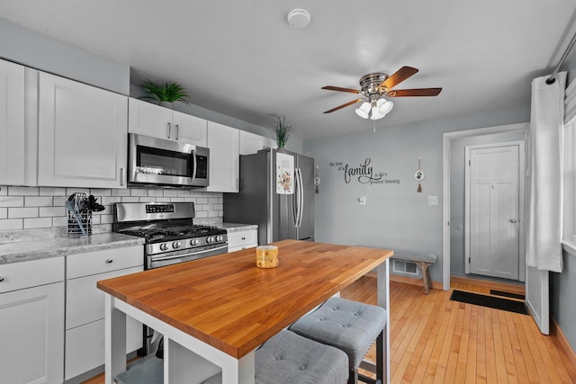 kitchen with visible vents, backsplash, ceiling fan, stainless steel appliances, and white cabinetry