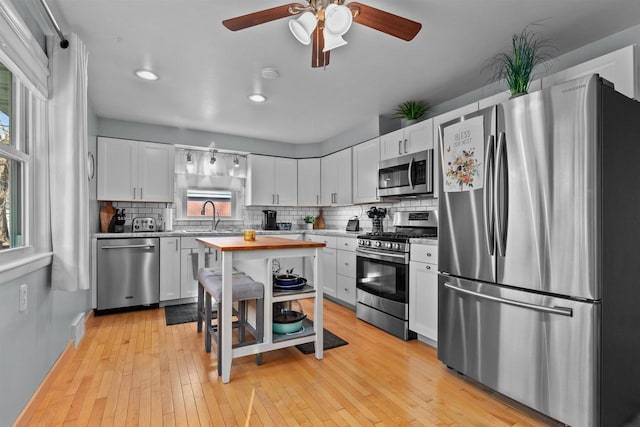 kitchen with decorative backsplash, appliances with stainless steel finishes, light wood-style floors, and a sink