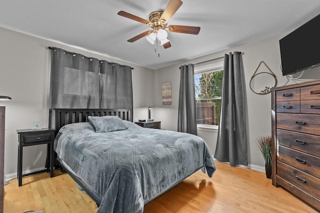 bedroom featuring baseboards, light wood-style floors, and a ceiling fan