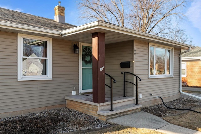 property entrance with a chimney and a shingled roof