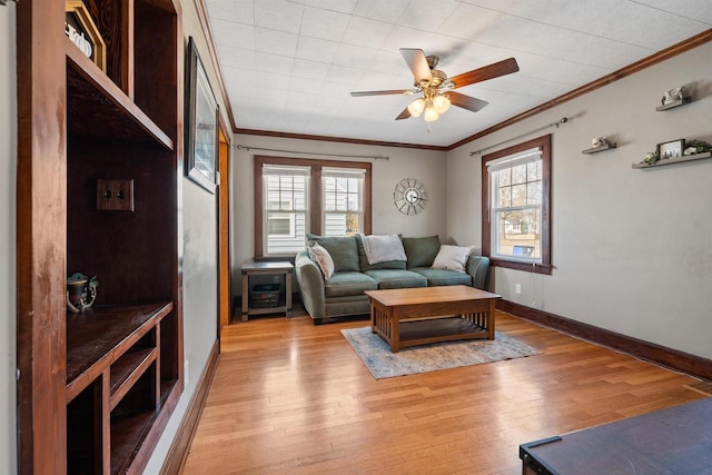 living area with baseboards, light wood-style floors, a ceiling fan, and crown molding