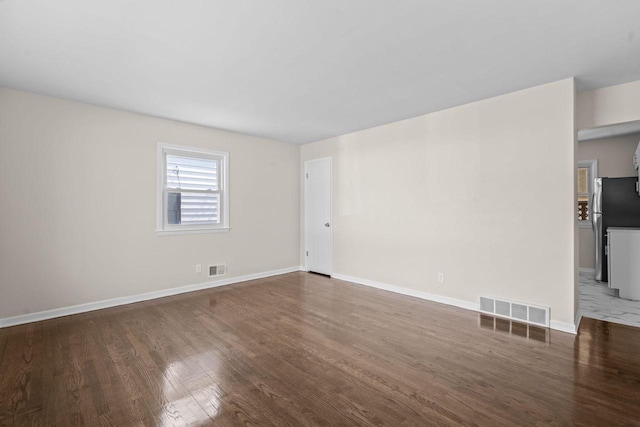 spare room featuring visible vents, baseboards, and wood finished floors