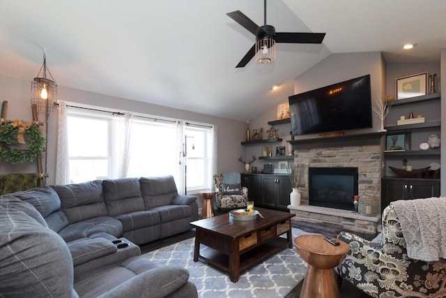 living area with a ceiling fan, wood finished floors, a fireplace, and vaulted ceiling