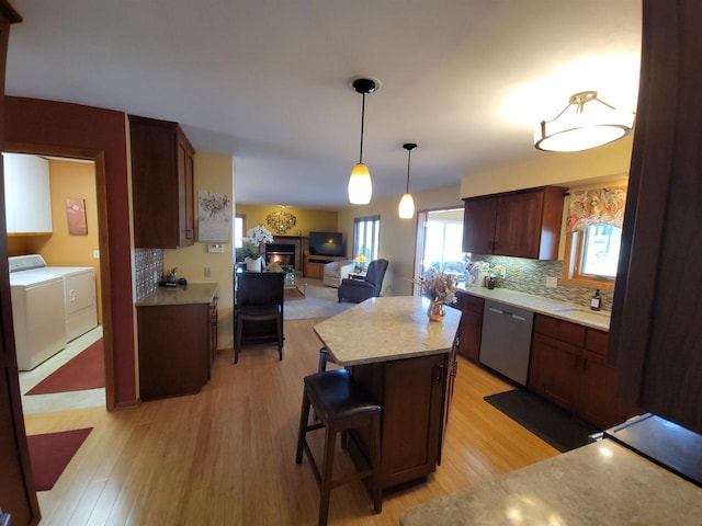 kitchen with light wood-type flooring, washer and dryer, backsplash, light countertops, and dishwasher