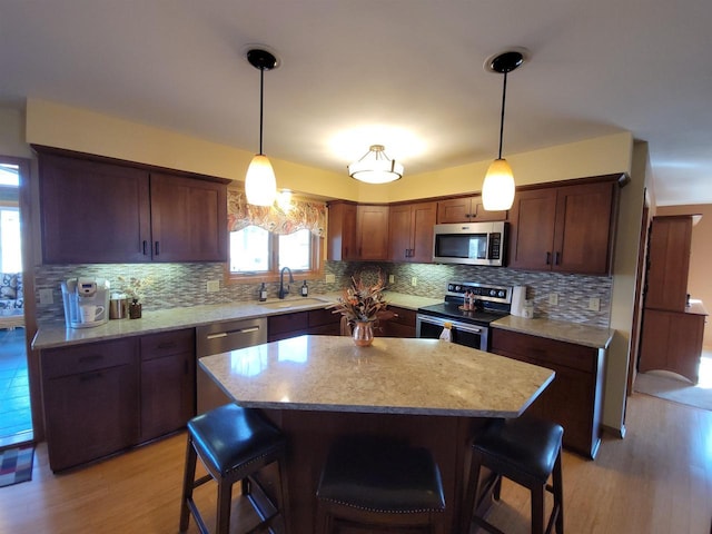 kitchen featuring tasteful backsplash, a breakfast bar, light wood-type flooring, appliances with stainless steel finishes, and a sink