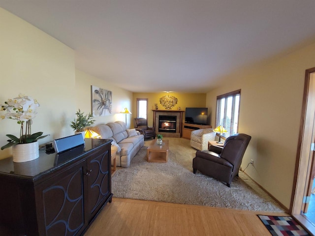 living room featuring a glass covered fireplace, light wood-style flooring, and a healthy amount of sunlight