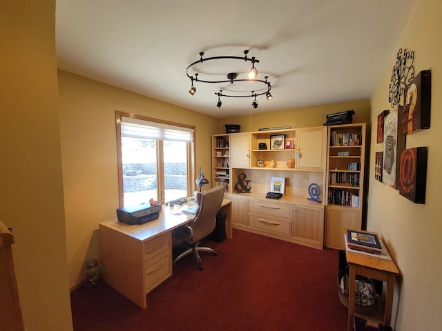 home office featuring track lighting, dark carpet, and built in study area