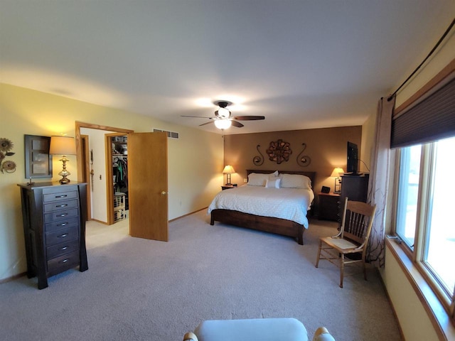 bedroom featuring a ceiling fan, visible vents, baseboards, a spacious closet, and light colored carpet