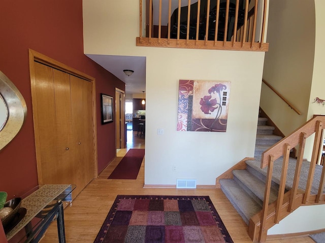 foyer entrance with a high ceiling, stairway, wood finished floors, and visible vents