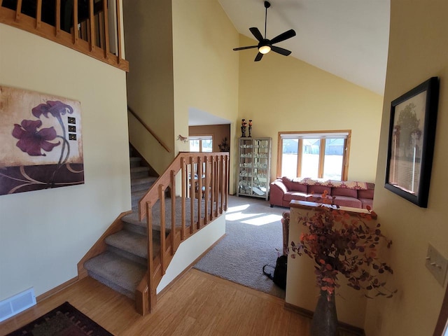 stairs featuring visible vents, high vaulted ceiling, a ceiling fan, and wood finished floors