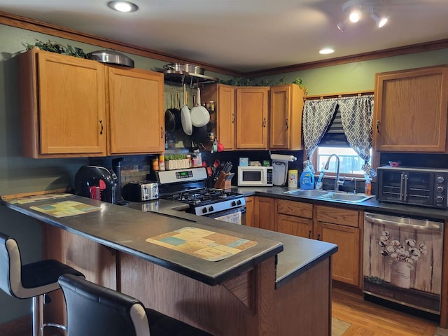 kitchen featuring ornamental molding, a sink, stainless steel appliances, a peninsula, and a breakfast bar area