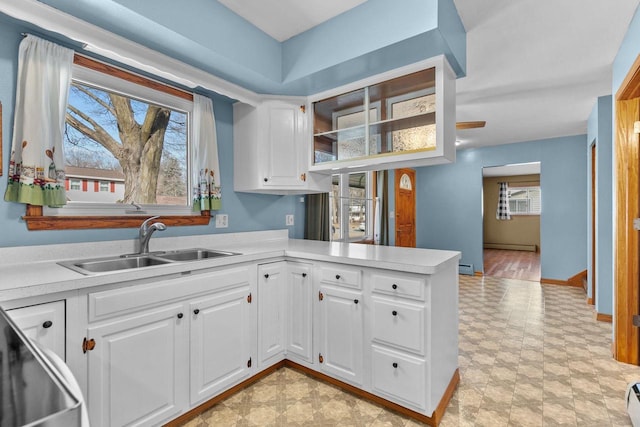 kitchen featuring baseboards, a sink, light countertops, white cabinetry, and baseboard heating