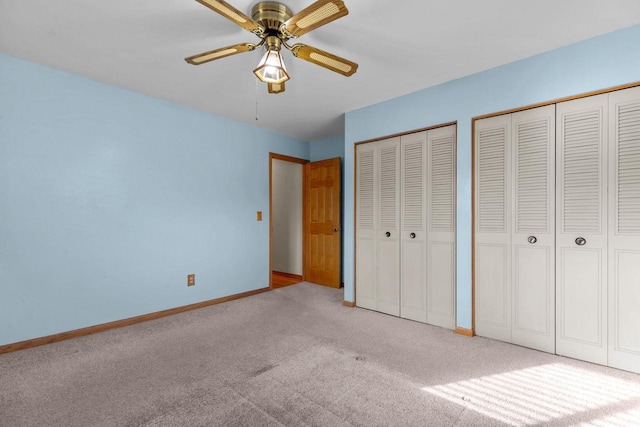 unfurnished bedroom with baseboards, carpet floors, two closets, and ceiling fan