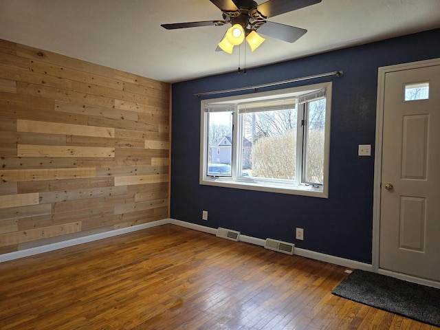 unfurnished room with a ceiling fan, baseboards, visible vents, and wood-type flooring