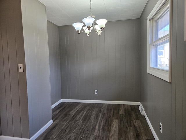 spare room featuring baseboards, a chandelier, and dark wood finished floors