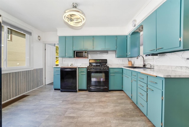 kitchen featuring a wainscoted wall, a sink, black appliances, light countertops, and under cabinet range hood