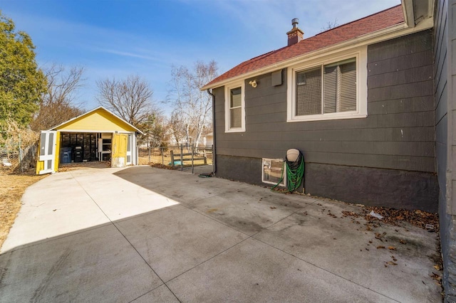 view of side of property with an outbuilding, a chimney, and fence