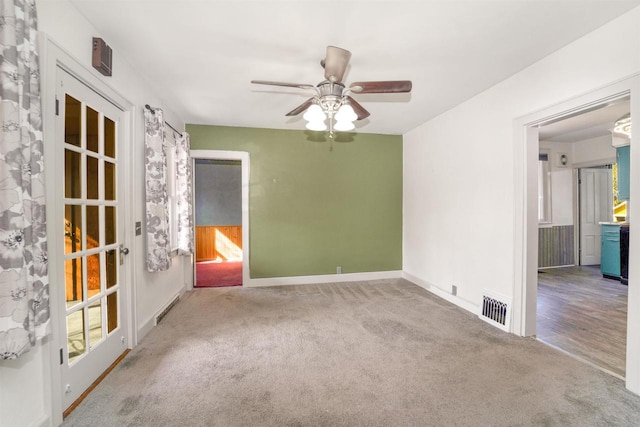 carpeted empty room featuring baseboards, visible vents, and ceiling fan