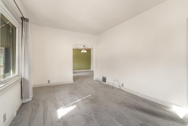 carpeted empty room with a ceiling fan, visible vents, and baseboards