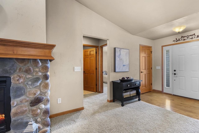 carpeted entrance foyer featuring lofted ceiling, wood finished floors, and baseboards