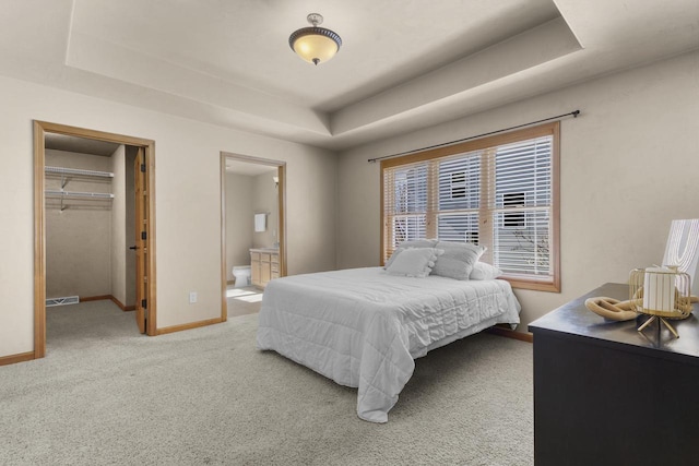 carpeted bedroom featuring a spacious closet, visible vents, baseboards, a tray ceiling, and a closet