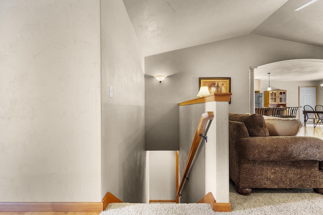 stairway featuring vaulted ceiling and arched walkways