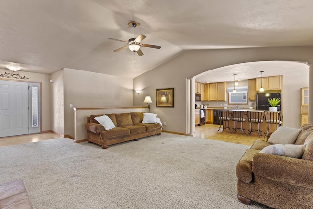 living area featuring light carpet, lofted ceiling, a ceiling fan, arched walkways, and baseboards