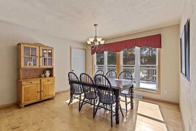 dining space featuring a notable chandelier, light wood-style flooring, baseboards, and visible vents