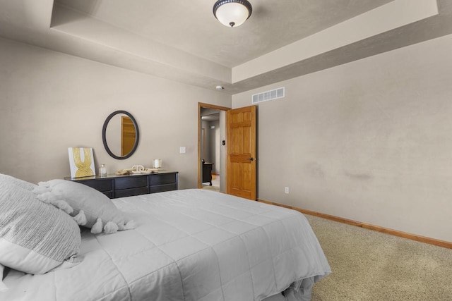 bedroom with a tray ceiling, baseboards, carpet floors, and visible vents