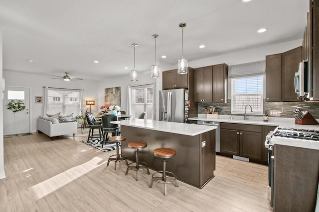 kitchen with a sink, dark brown cabinetry, appliances with stainless steel finishes, and a center island