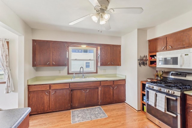 kitchen featuring a sink, light wood finished floors, range with two ovens, white microwave, and ceiling fan