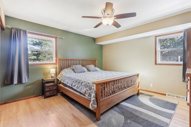 bedroom with ceiling fan, visible vents, baseboards, and wood finished floors