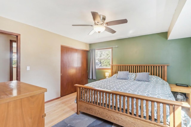 bedroom featuring a closet, baseboards, ceiling fan, and wood finished floors