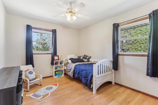 bedroom featuring light wood-style flooring, baseboards, and ceiling fan