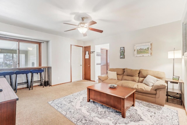 carpeted living room with baseboards and a ceiling fan