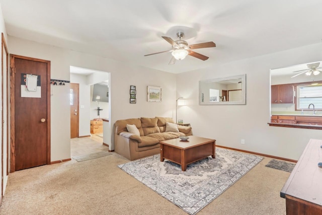 living room with baseboards, light colored carpet, and ceiling fan