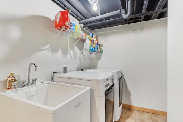 laundry area with baseboards, washing machine and clothes dryer, laundry area, light tile patterned flooring, and a sink