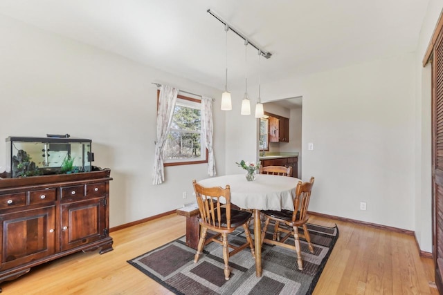 dining space with rail lighting, baseboards, and light wood-style floors